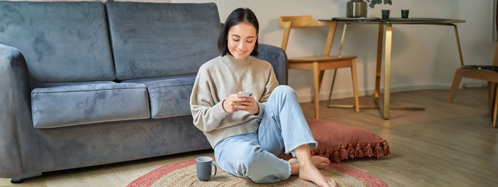 Portrait of young woman sitting on sofa at home