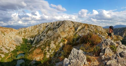 Rear view of man standing on cliff against sky