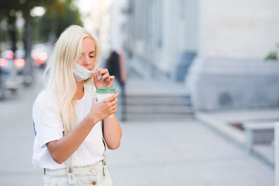 Young woman wearing mask holding coffee cup