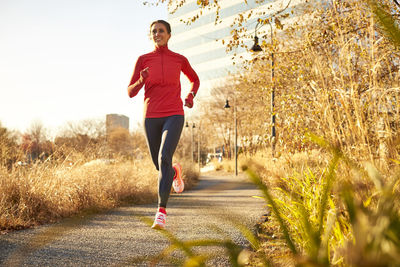 A woman running in an urban park on a bright autumnal day.