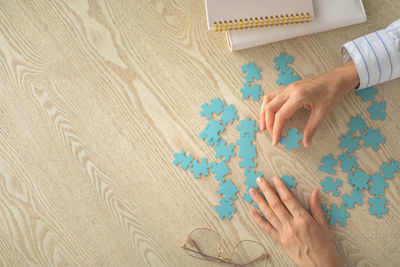 Cropped hand of person holding jigsaw pieces on table