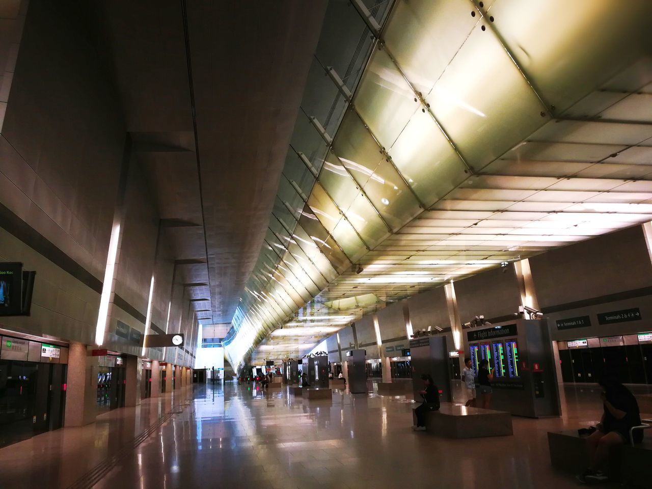 PEOPLE WAITING IN ILLUMINATED CORRIDOR