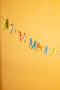 Low angle view of clothespin hanging against yellow background