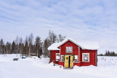 House on snow covered field against sky