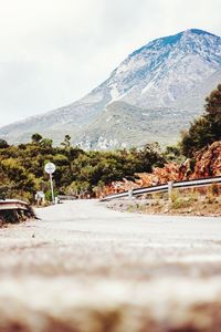 Man on road by mountains against sky