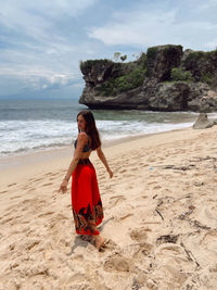 Full length on woman standing at beach against sky