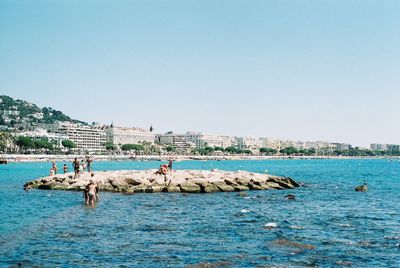 People on beach against clear sky