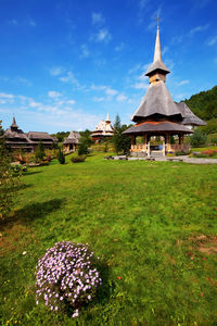 Low angle wide shot of garden surrounding monastery against blue sky