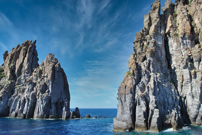 Panoramic view of rocks by sea against sky