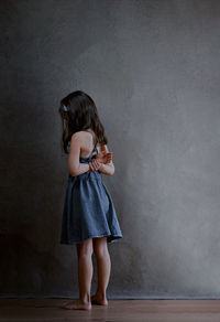 Punished girl stands in the corner and is offended by the whole world, rear view of a girl dark hair