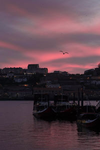 Scenic view of sea against buildings at sunset