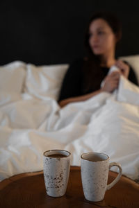 Woman with coffee cup on bed