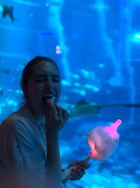 Woman eating cotton candy while standing in aquarium