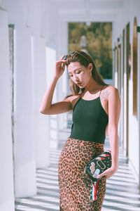 Beautiful young woman standing against wall