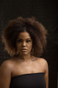 Portrait of young woman against black background