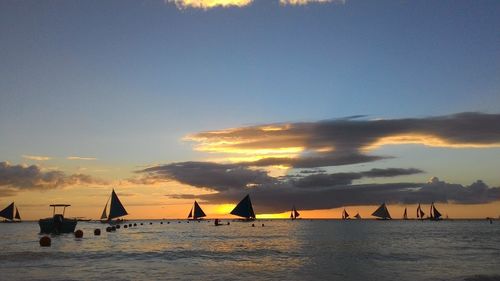 Silhouette sailboats sailing on sea against sky during sunset