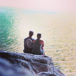 Rear view of people sitting on rocks