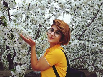 Portrait of smiling young woman standing against trees