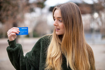 Woman holding credit card while standing in park