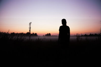 Rear view of silhouette woman standing against sky during sunset