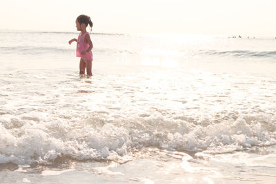 Girl standing in sea on shore at beach