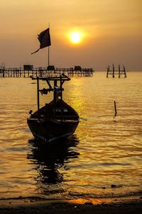 Boat moored on sea against sky during sunset