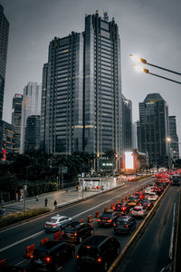 Traffic on road amidst buildings in city against sky