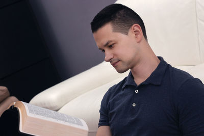 Young man looking away while sitting on book