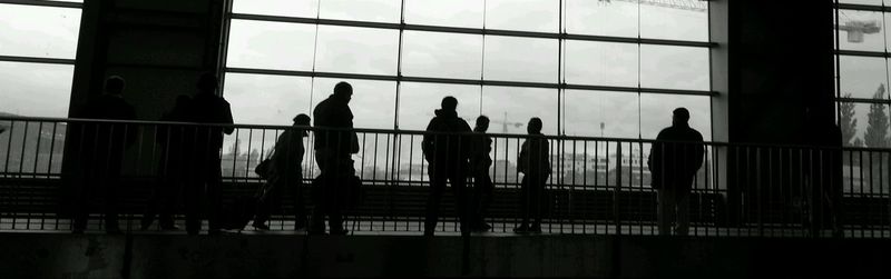 Silhouette people standing by window in city