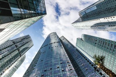 Low angle view of modern buildings against cloudy sky