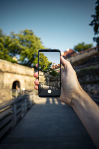 Man photographing through smart phone against sky