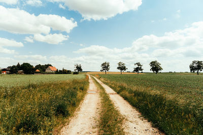 Road amidst field against sky