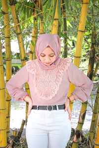 Portrait of young woman standing against plants