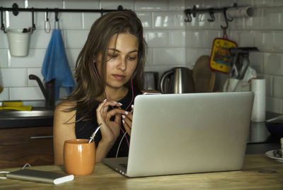 Young woman using phone while sitting at table