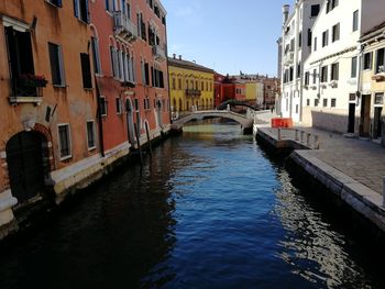 Canal amidst buildings in city against sky