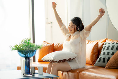 Side view of woman using digital tablet while sitting on sofa at home