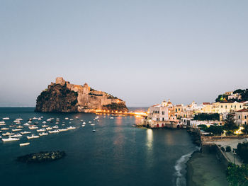 Buildings by sea at dusk