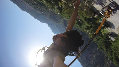 Low angle view of woman holding rope against trees