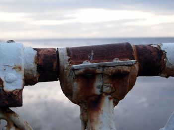 Close-up of rusty metal by sea against sky