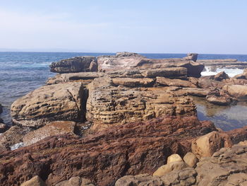 Rock formations on shore against sky