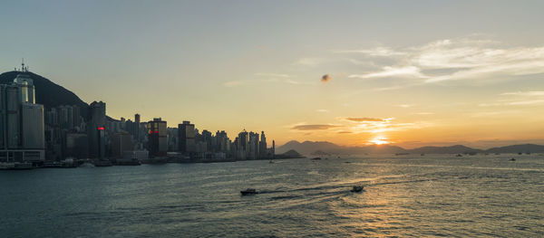 Scenic view of sea and buildings against sky during sunset