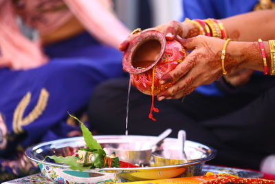 Cropped hand pouring water in container during religious event