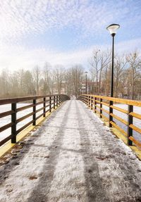 Snow covered footbridge against sky