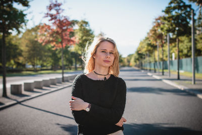 Beautiful young woman standing on road during sunny day