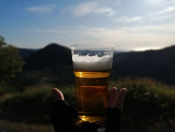 Drinking glass of beer on table against sky