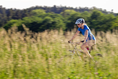 Side view of woman cycling amidst field