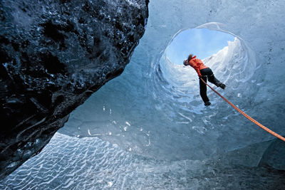 Woma rappelling into glacier cave on sólheimajökull glacier in iceland