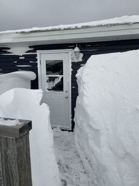 Snow covered house by building against sky