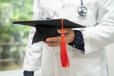 Midsection of woman wearing graduation gown