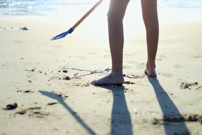 Low section of boy holding toy while standing at beach